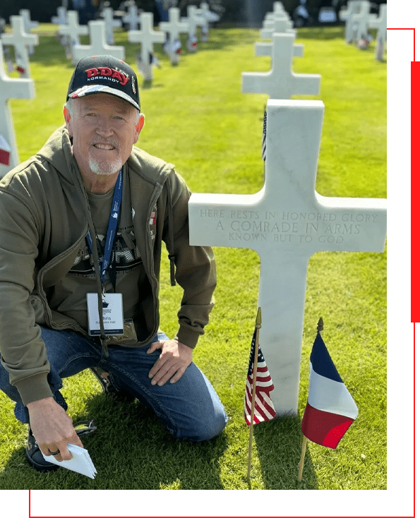 A man kneeling next to a white cross.