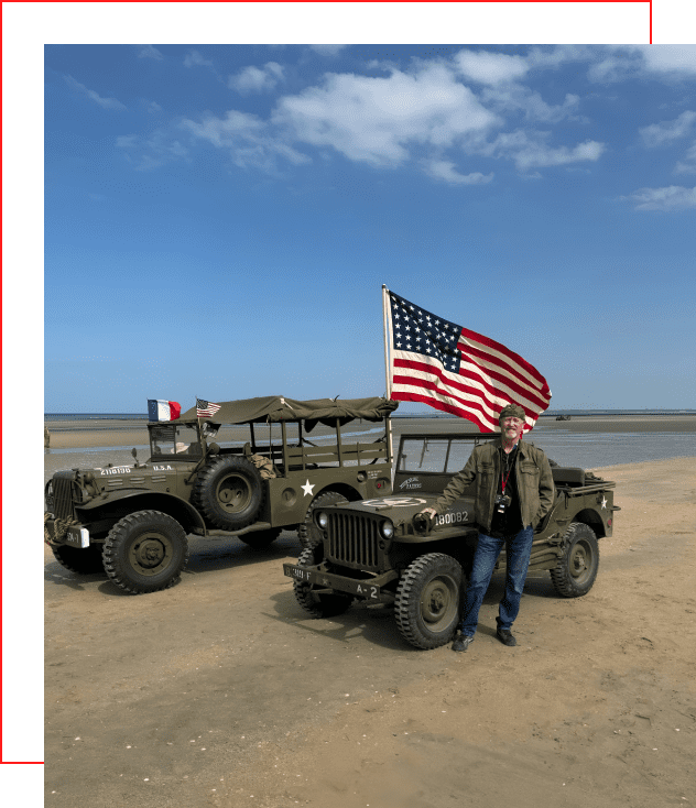 A man standing next to two military vehicles.